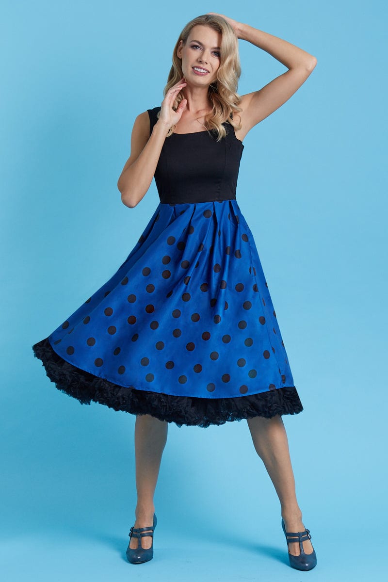 Model wears our sleeveless swing dress, in black, dark blue polka dot print, front view,