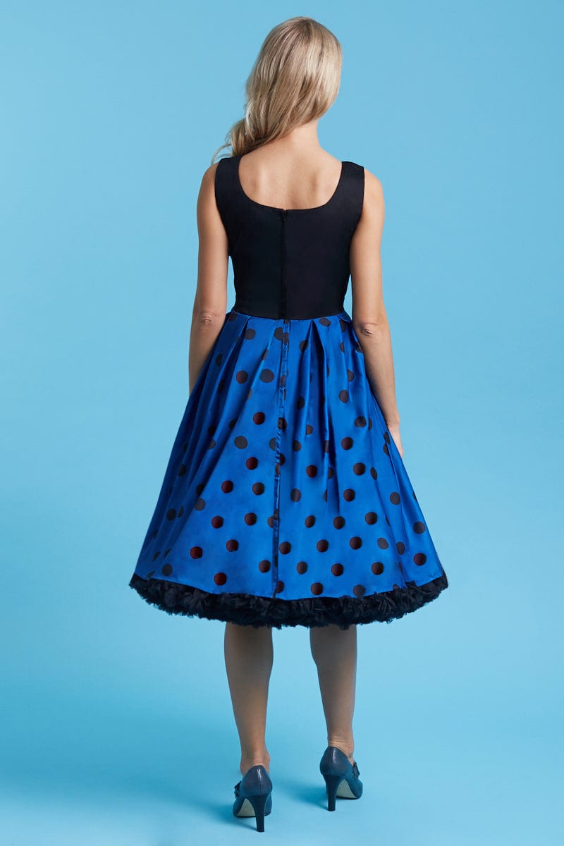 Model wears our sleeveless swing dress, in black, dark blue polka dot print, back view
