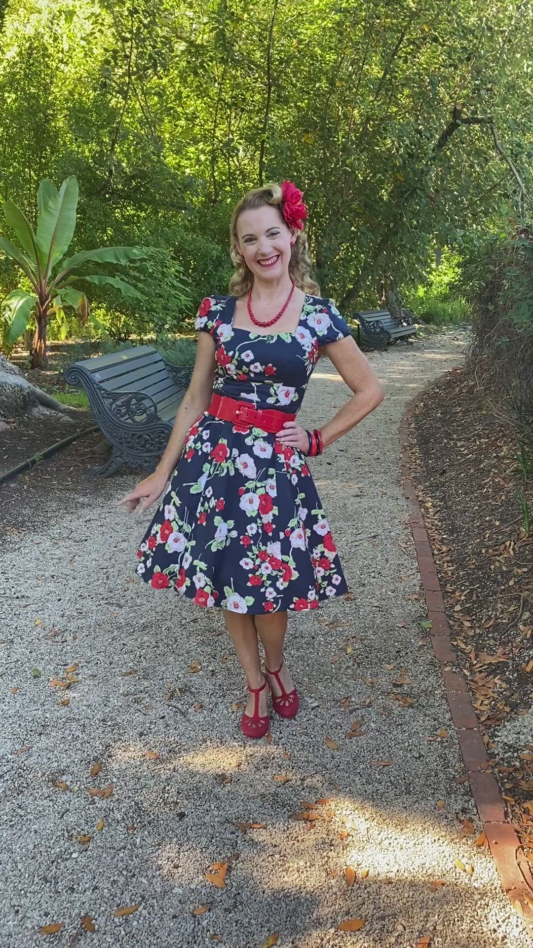 Video of a model posing playfully, wearing our Claudia Navy & White Red Floral Swing Dress.