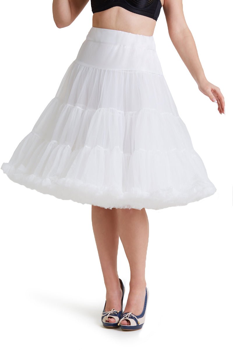 Woman wears white knee length petticoat, with black accessories, front view