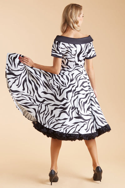 Model wears our short sleeve flared dress, in white and black zebra print, with a black petticoat, back view