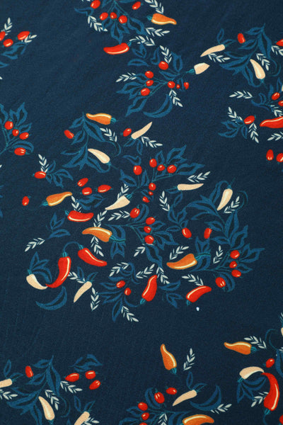 Fabric view of short sleeved blue midi dress, with red chili print