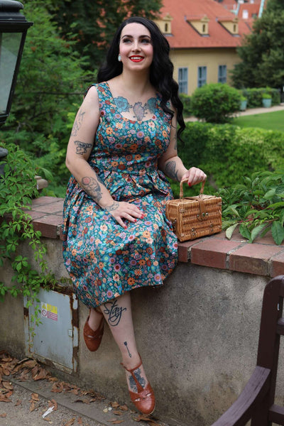 A lady wearing an Amanda 70s Floral Swing Dress In Peacock Blue