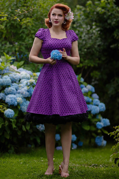 A lady wearing a Flirty Fifties Polka Dot Dress in Purple-Black