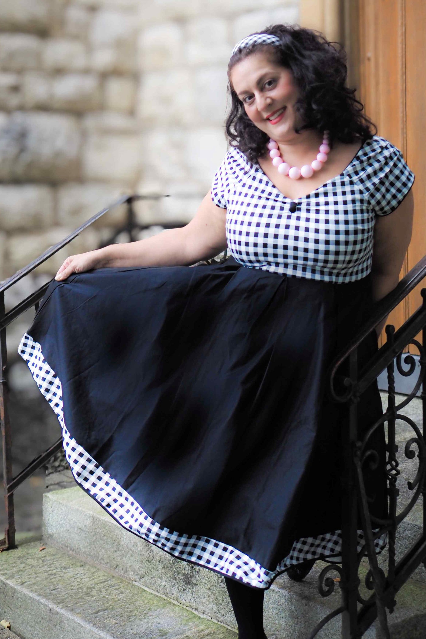A lady wearing a Lily Off Shoulder Black/White Gingham Swing Dress
