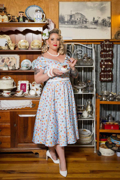 A model wearing Blue Gingham Off Shoulder Dress In Baking Print