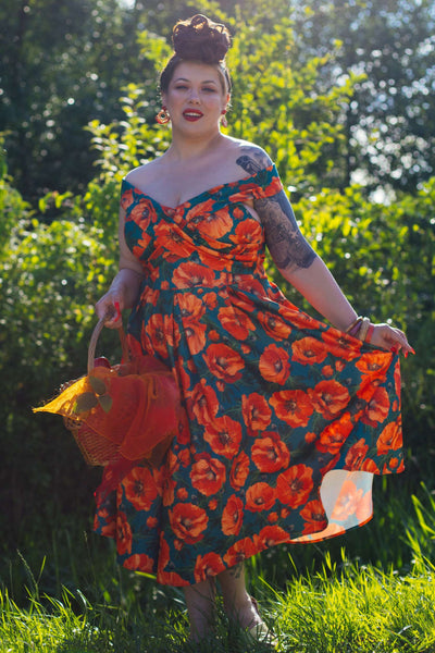 A lady wearing a Beverly Orange Poppy Off Shoulder Dress In Green