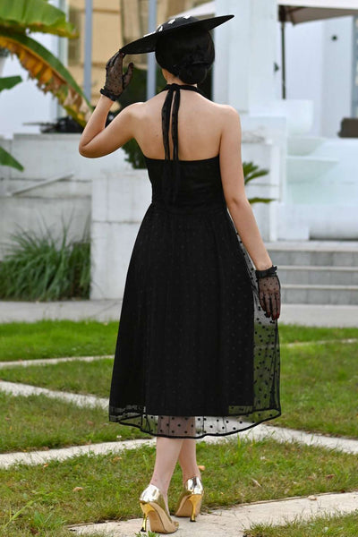 A model wearing a Dorothea Black Polka Dot Mesh Halter Dress