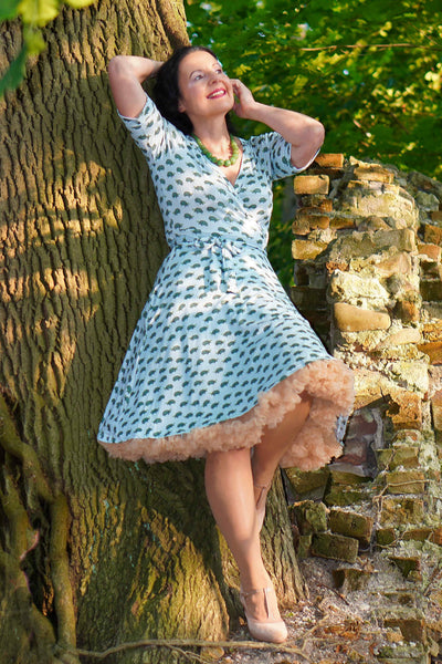 A model wearing Blue Sea Turtle Wrap Dress leans against a tree