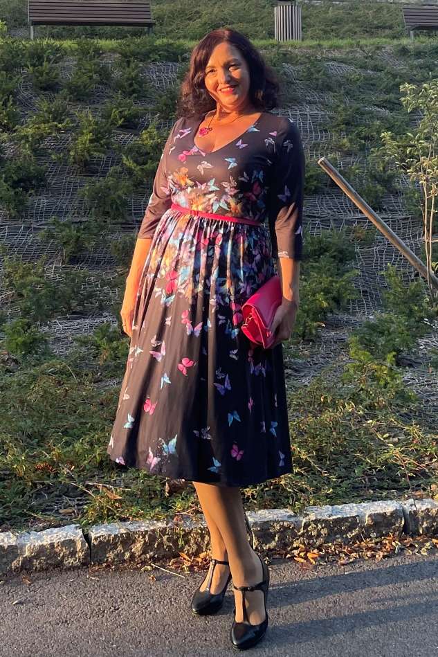 A woman wearing a Billie Black Butterfly Long Sleeved Dress