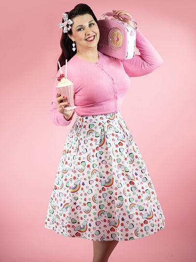Model in a pink cardigan, rainbow print skirt, with a milkshake