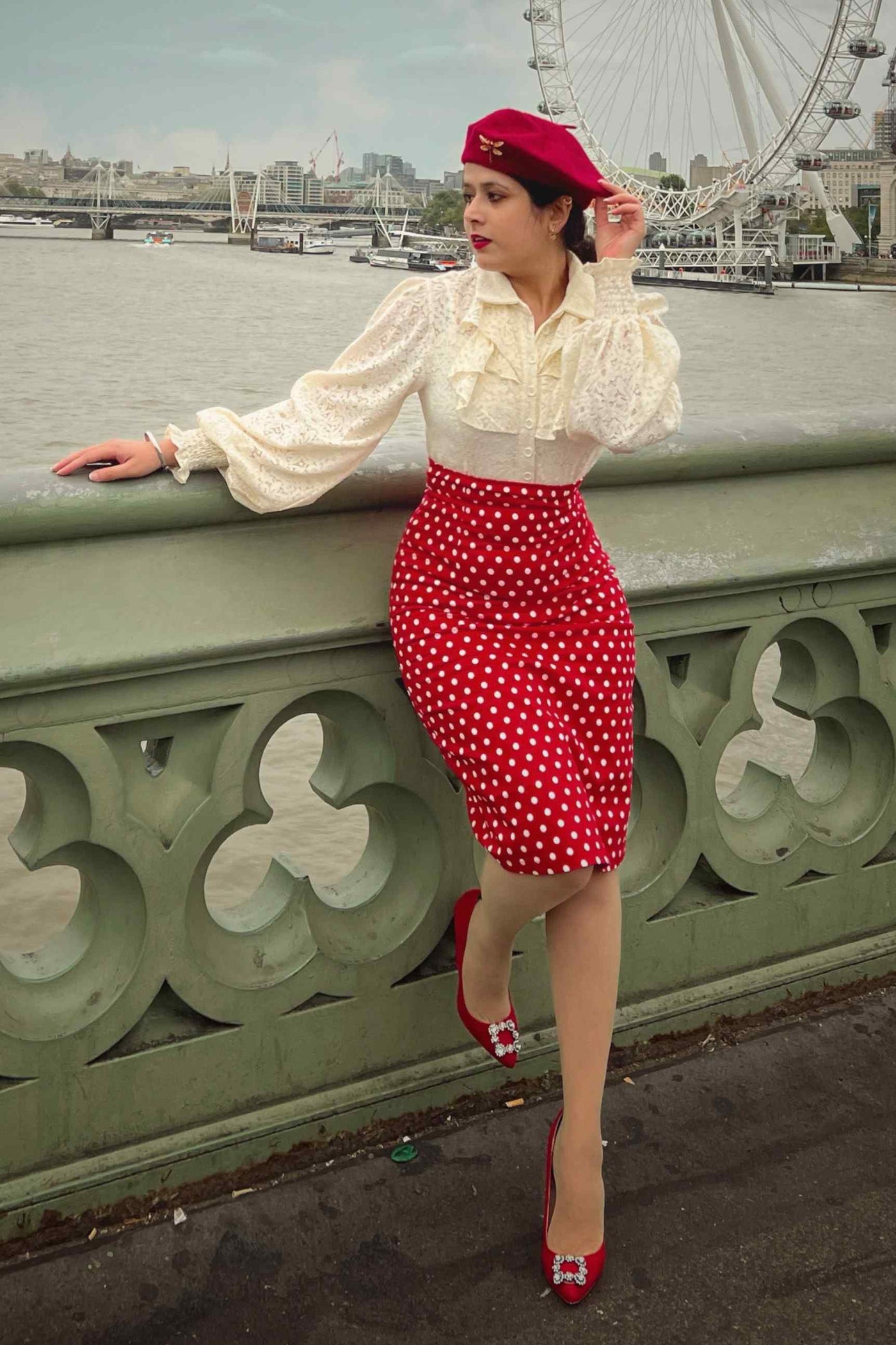 Woman wearing our red and white polka dot pencil skirt, with matching accessories and top, on a bridge in London
