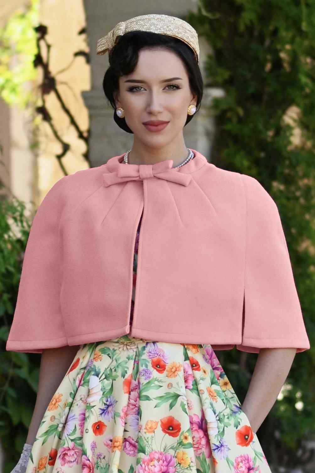 A woman wearing a Sabrina Coral Pink Cape Jacket