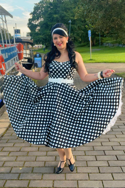 A laday wearing a Daisy Black Polka Dot Halter Dress