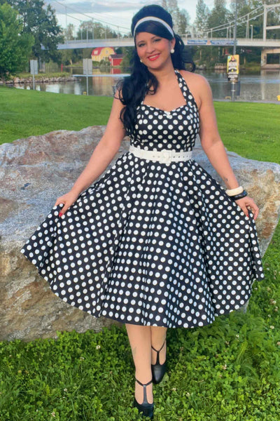 A model wearing a Daisy Black Polka Dot Halter Dress