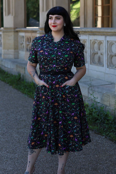 A lovely model wearing a Mabel Dinosaur & Rainbow Midi Shirt Dress In Black