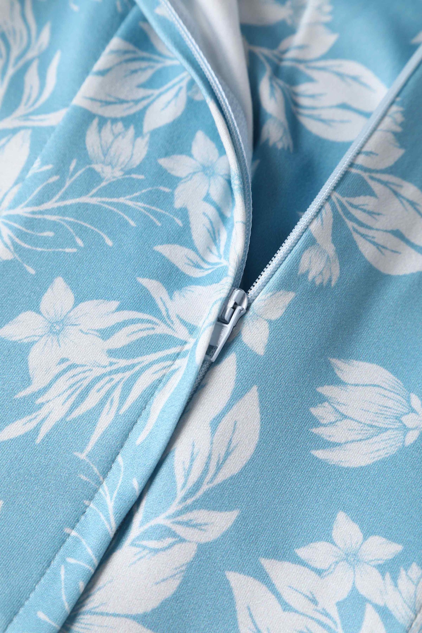Close up of light blue, with white floral fabric and zip