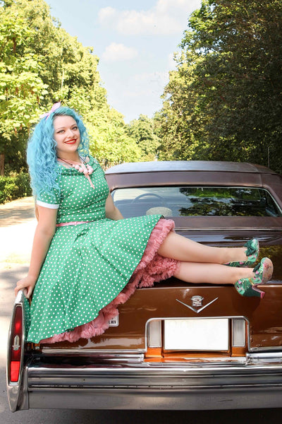 A model wearing a Full Circle Green Polka Dot Swing Dress sits in the back of a car