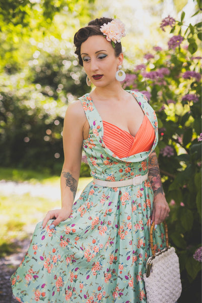 A lady wearing a Green Floral Dragonfly Pleated Bust Dress