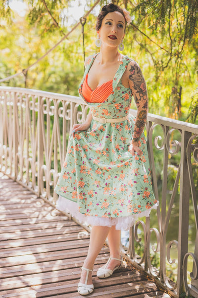 A lady wearing a Green Floral Dragonfly Pleated Bust Dress