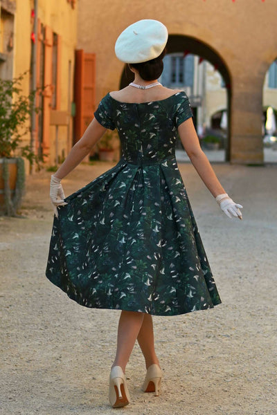 A model wearing a Lily Dark Green Off Shoulder Dress In Magpie Print