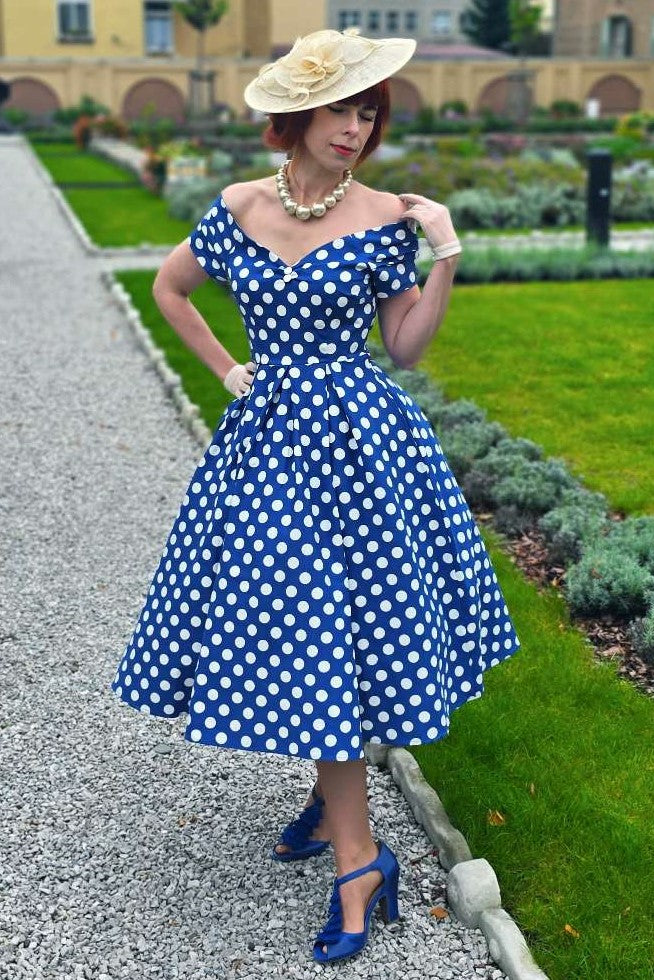 A lady wearing a Lily Navy Blue Polka Dot Off Shoulder Dress