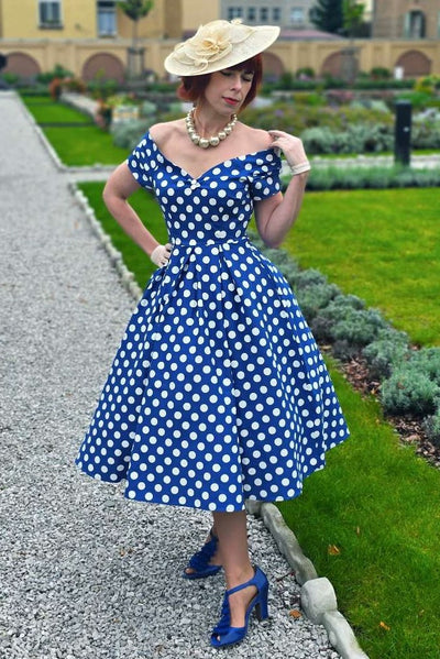 A lady wearing a Lily Navy Blue Polka Dot Off Shoulder Dress