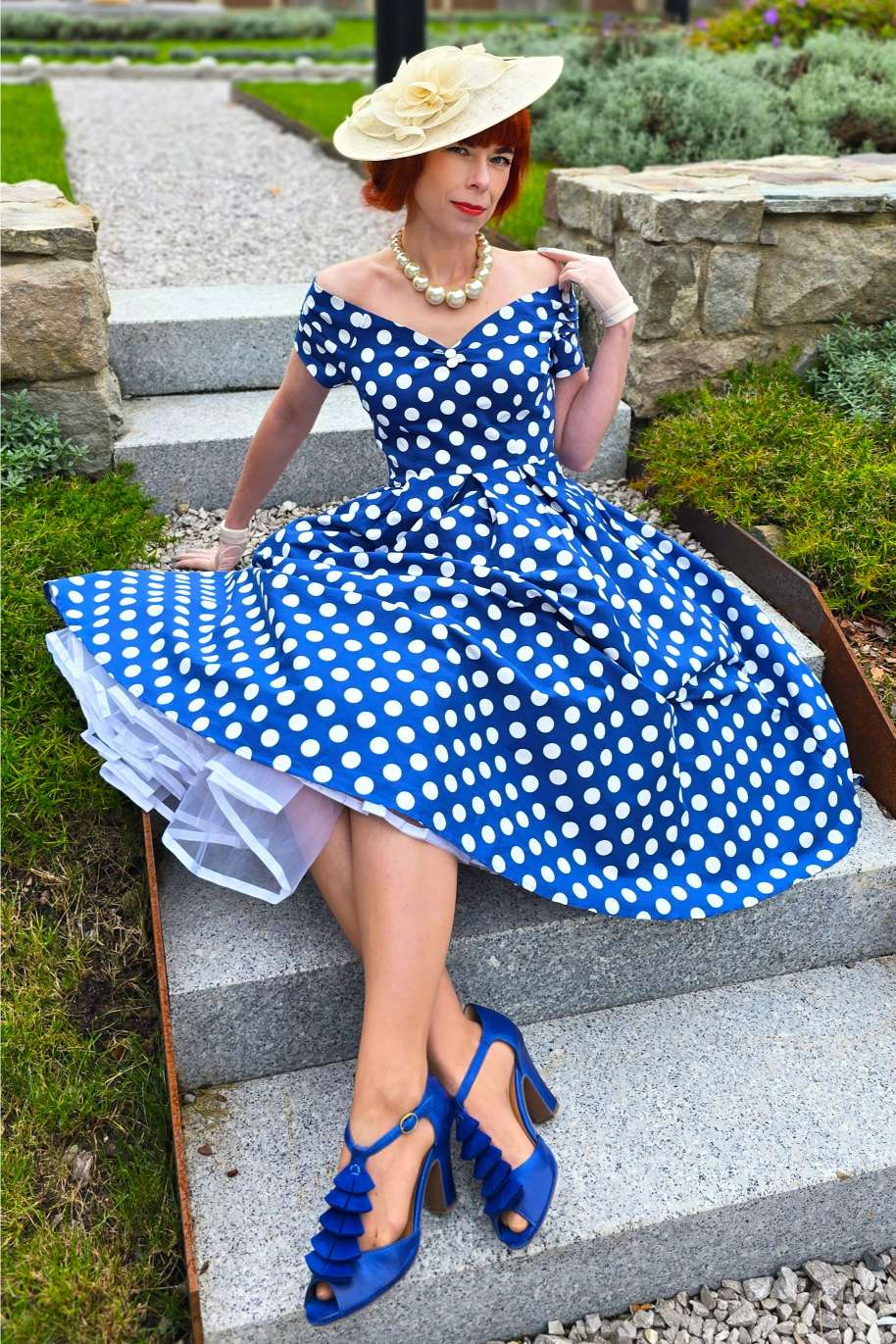 A woman wearing a Lily Navy Blue Polka Dot Off Shoulder Dress