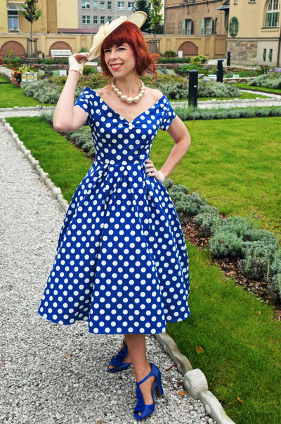 A model wearing a Lily Navy Blue Polka Dot Off Shoulder Dress