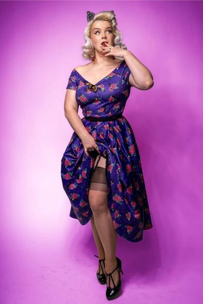 A lady wearing a Lily Vintage Cat & Rose Off Shoulder Dress In Purple