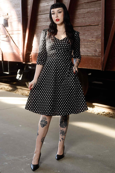 A model wearing Long Sleeve 50s Style Swing Dress in Black Polka