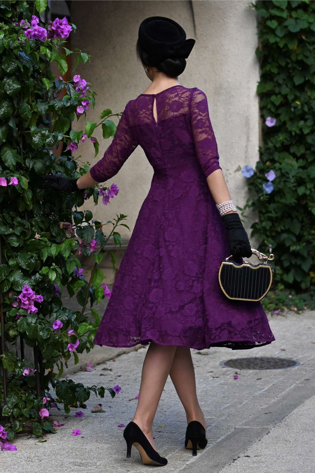 Back view of a woman wearing a Madeline Long Sleeved Purple Lace Dress