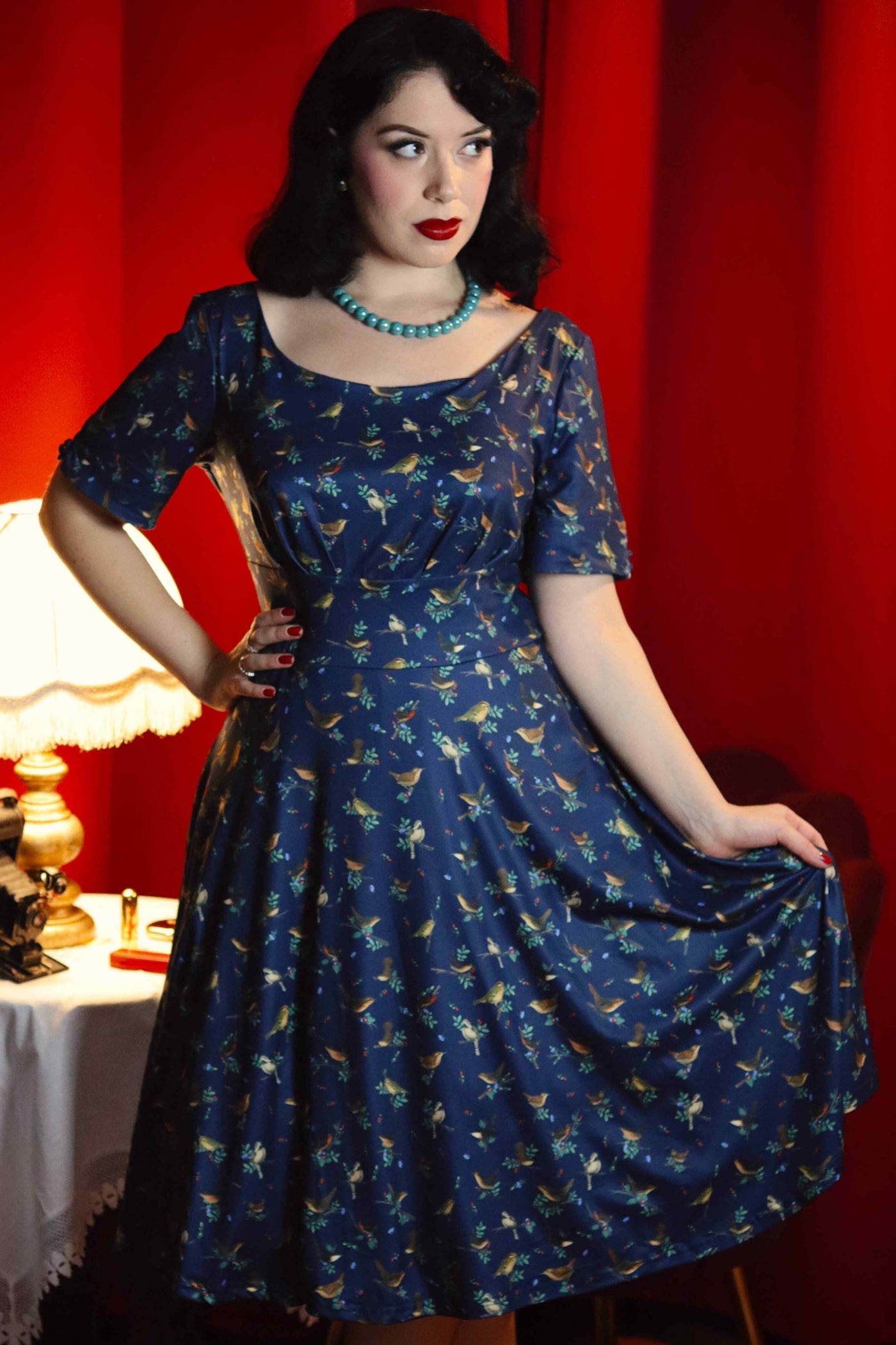 A model wearing a Brenda Navy Blue Bird Print Dress