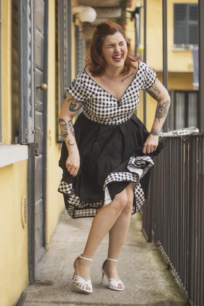 Woman wears our Lily Off Shoulder Black/White Gingham Swing Dress, whilst laughing