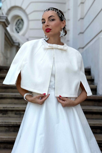 A lovely model wearing a Susan One Shoulder White Swing Dress with Sabrina Ivory White Cape Jacket