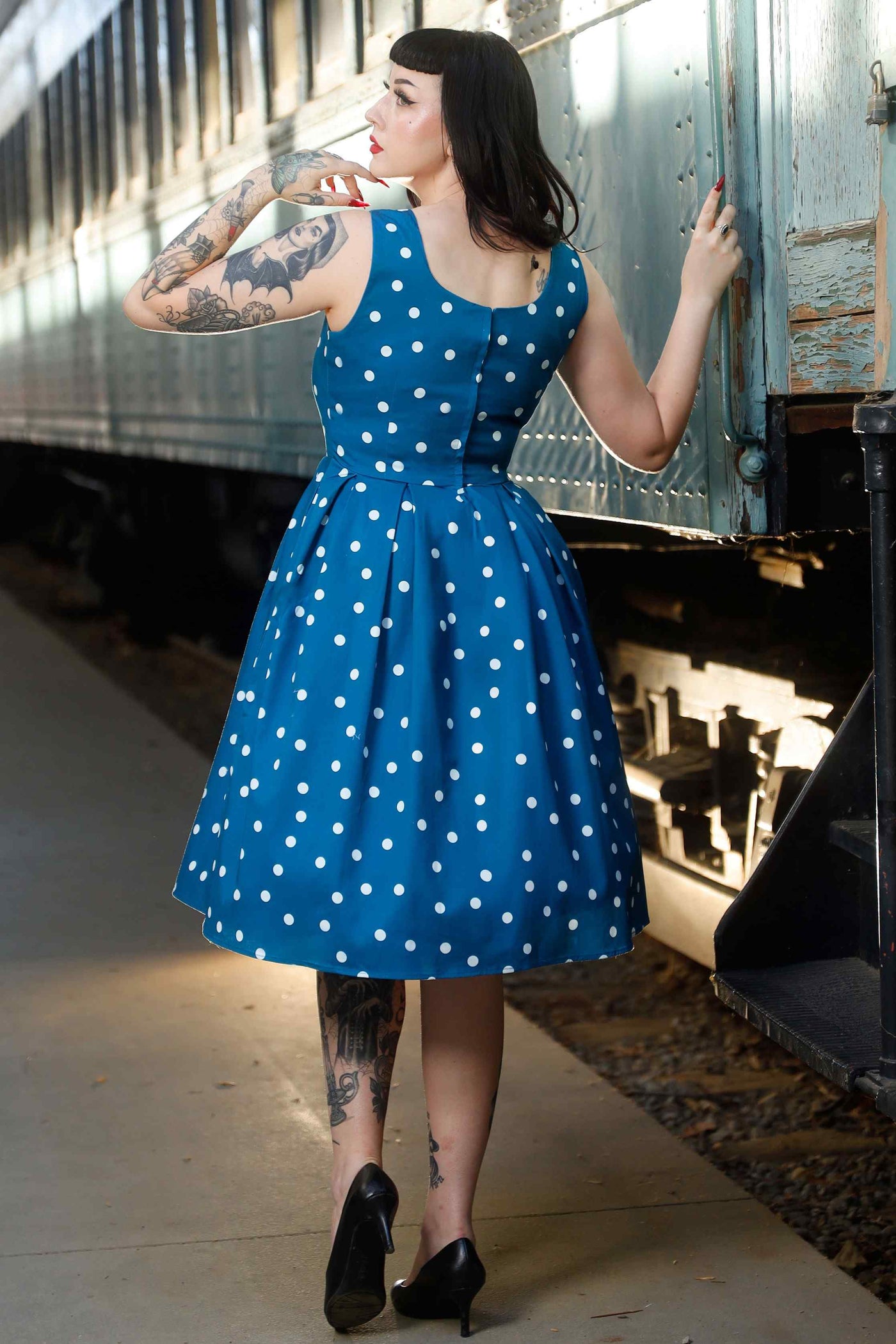Back view of model wearing Polka Dot Swing Dress Peacock Blue & White