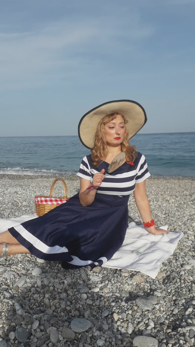 A video of tylosophia wearing our Darlene Nautical Navy & White Striped Swing Dress on a beach.
