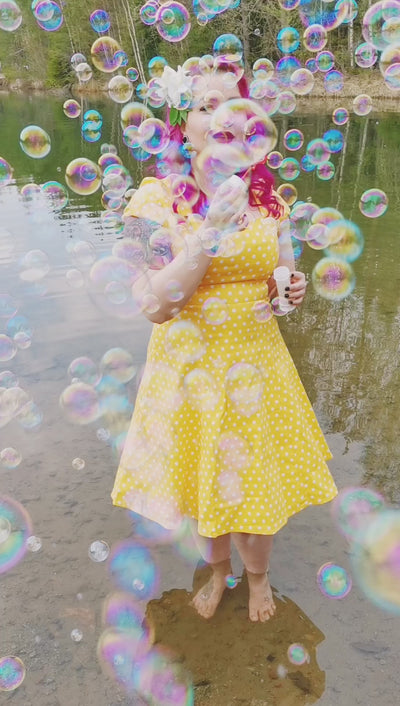 Video of Ms. skullshutterimages blowing bubbles in the river, wearing our Claudia Flirty Fifties Style Dress in Yellow