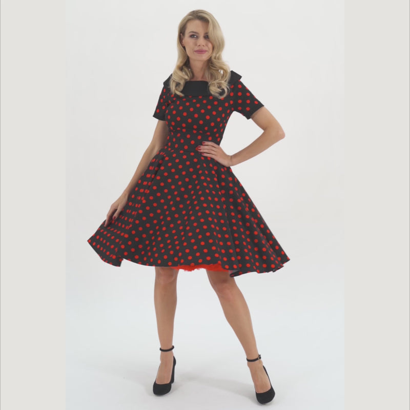 Model wearing Black Dress with red Polka dots, twirling.