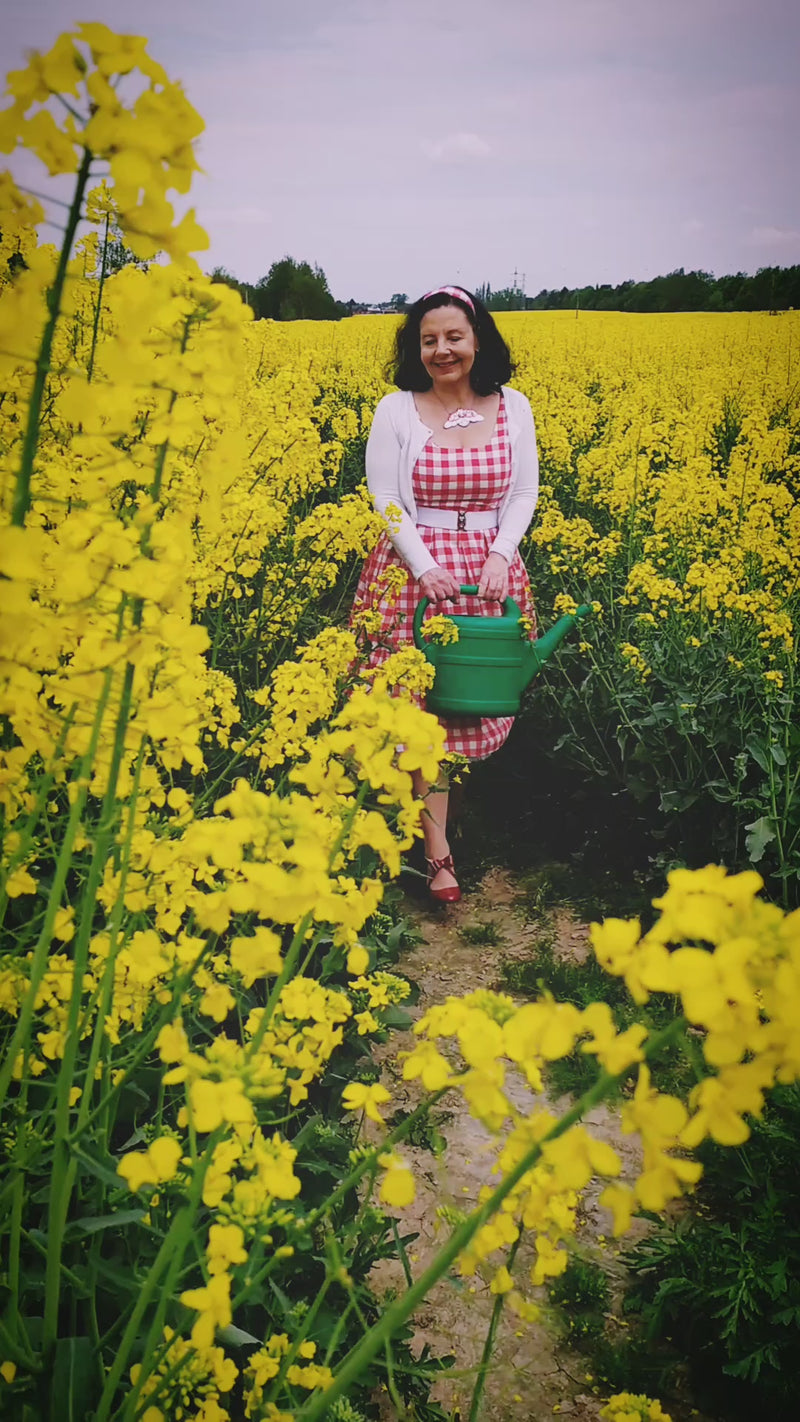Video of a model in a yellow poppy field wearing  a red and white checkered dress and  white cardigan.