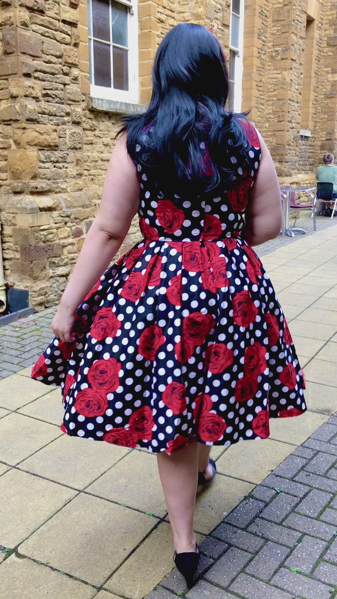 video of woman wearing our Elizabeth black party dress, with red roses and white spots