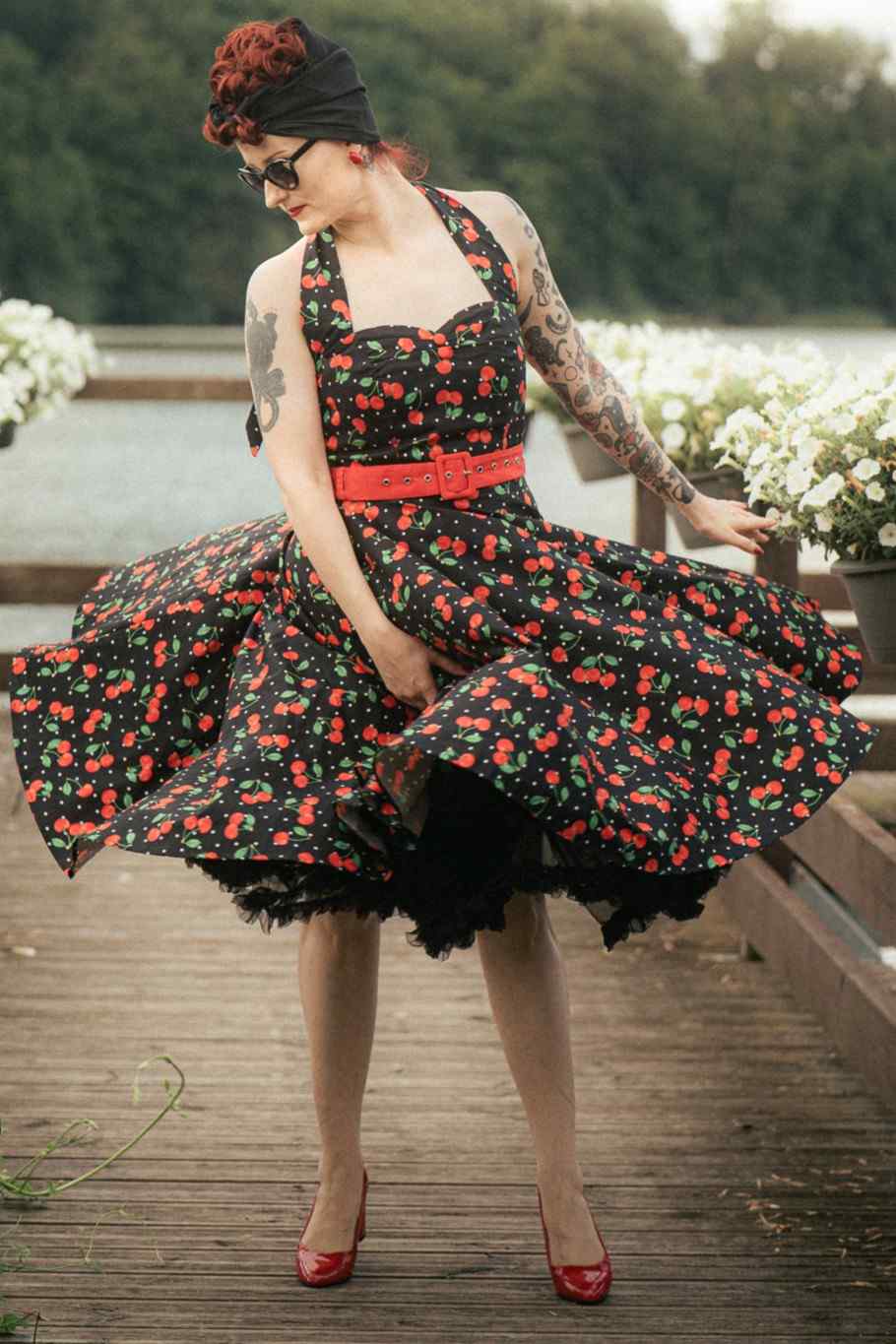 A model wearing a Daisy Red Cherry Halter Dress In Black