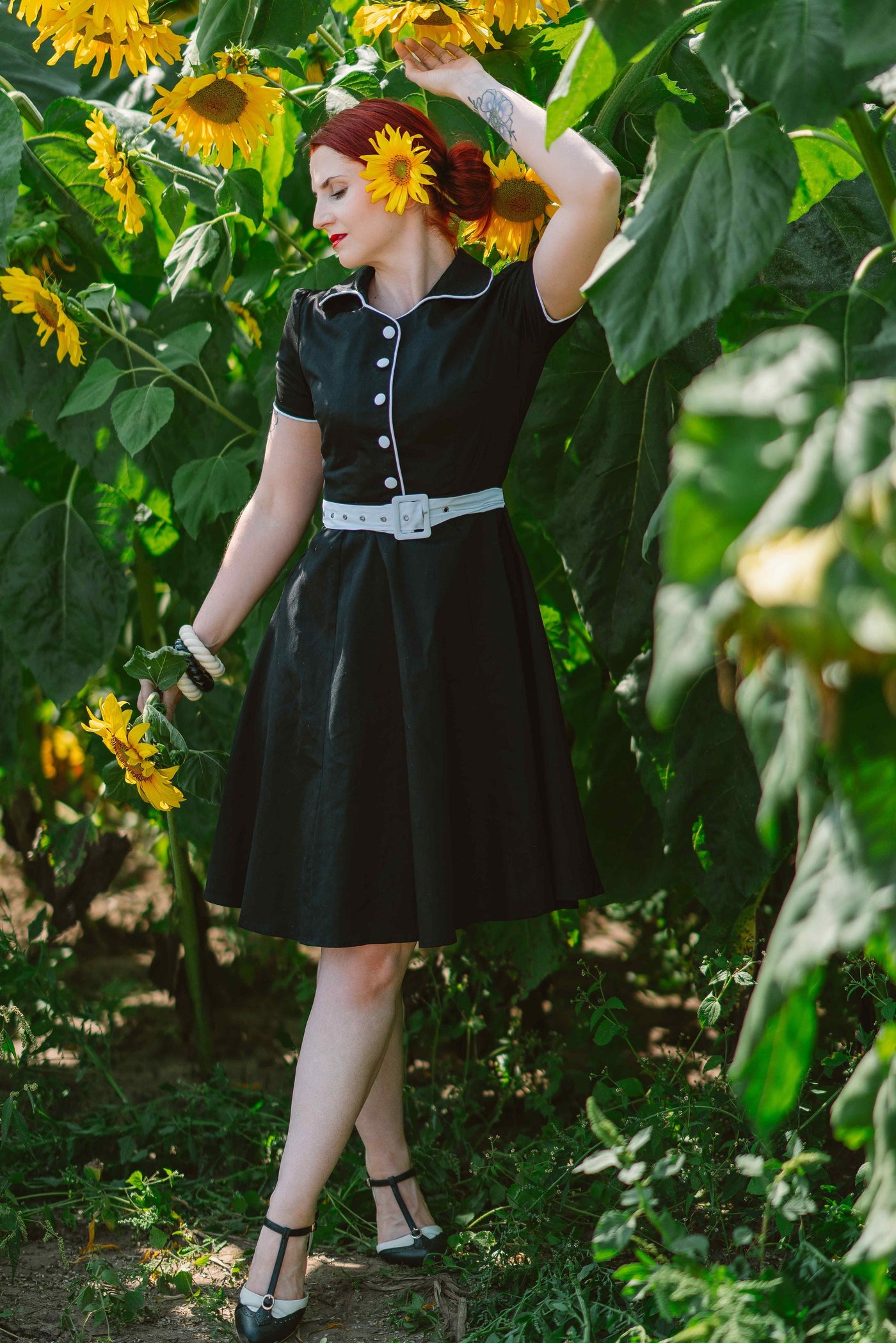 Woman wears our Short sleeve Penelope diner button top dress, in black and white, in a field of sunflowers
