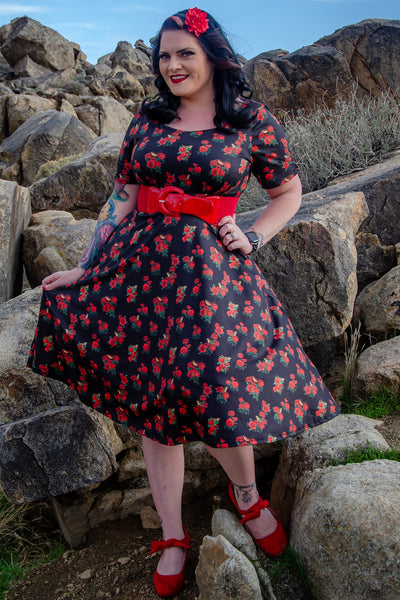 Customer wears our Brenda short sleeve dress in black red roses and birds print, on big rocks