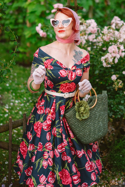 Woman wearing our V neck Lily dress, in navy blue, with pink tulips, with accessories, front view