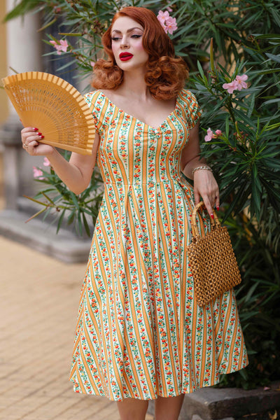 A model wearing a Sicilian Orange Stripe Swing Dress, holds skirt
