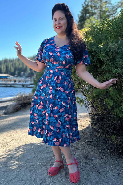 A model wearing a Sleeved Tea Dress In Blue Flamingo & Leaves Print