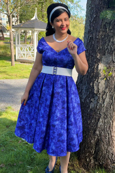 A lady wearing a Lily Blue Watercolour Floral Off Shoulder Dress