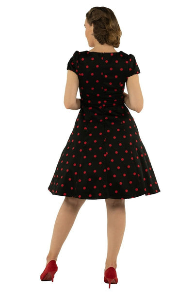 Model wears the Claudia cap sleeve dress in black, with red polka dots, back view