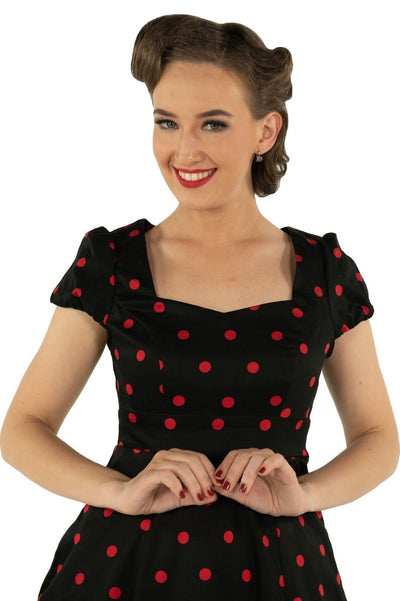 Model wears Claudia cap sleeve dress in black, with red polka dots, close up view